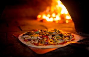 Delicious vegetarian pizza going into a wood fire oven