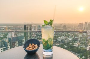 Mojito cocktail and cashews on table in rooftop bar